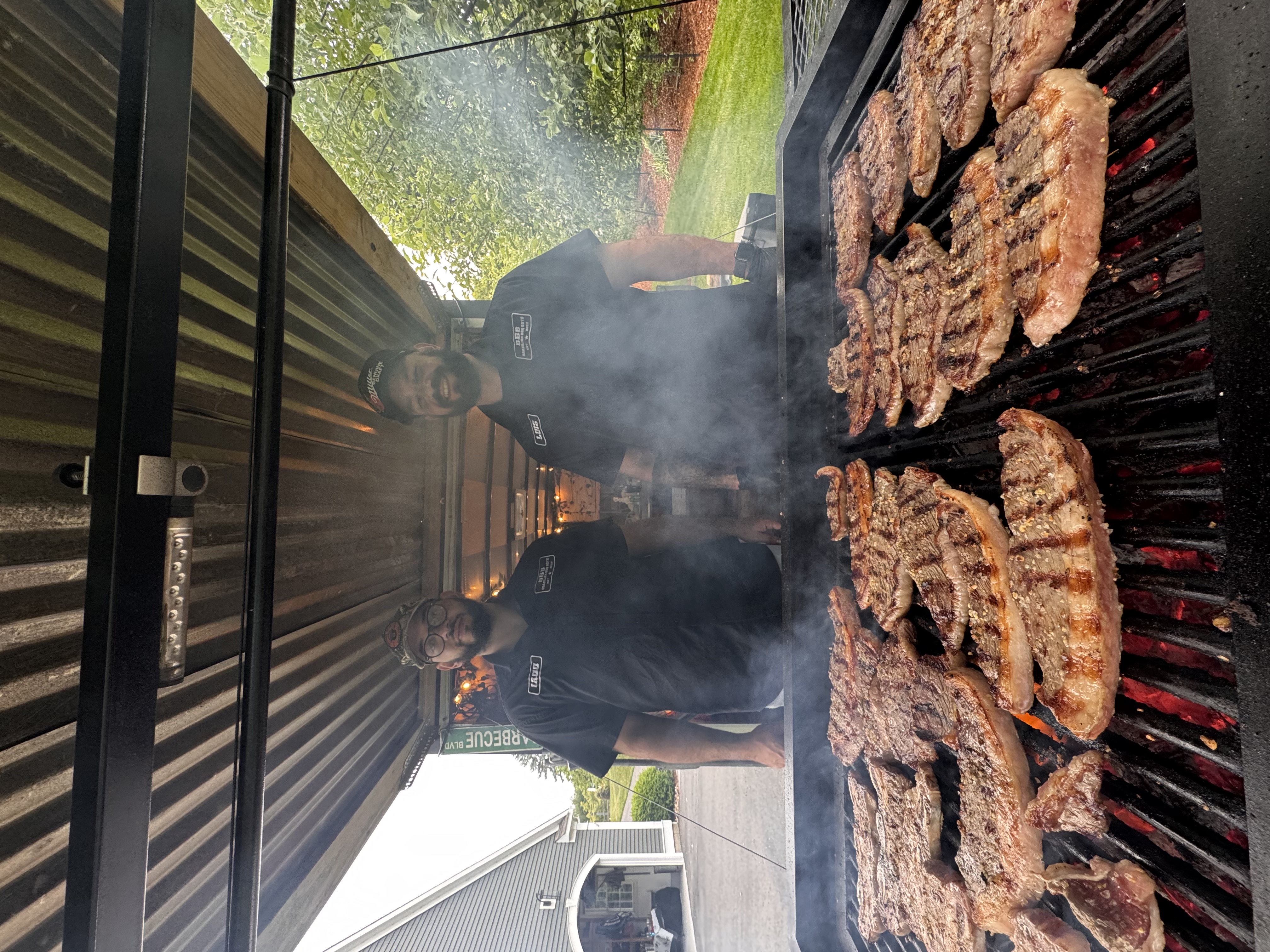 Iago and Luis standing in front of grill in trailer - Brazilian BBQ Boys founders